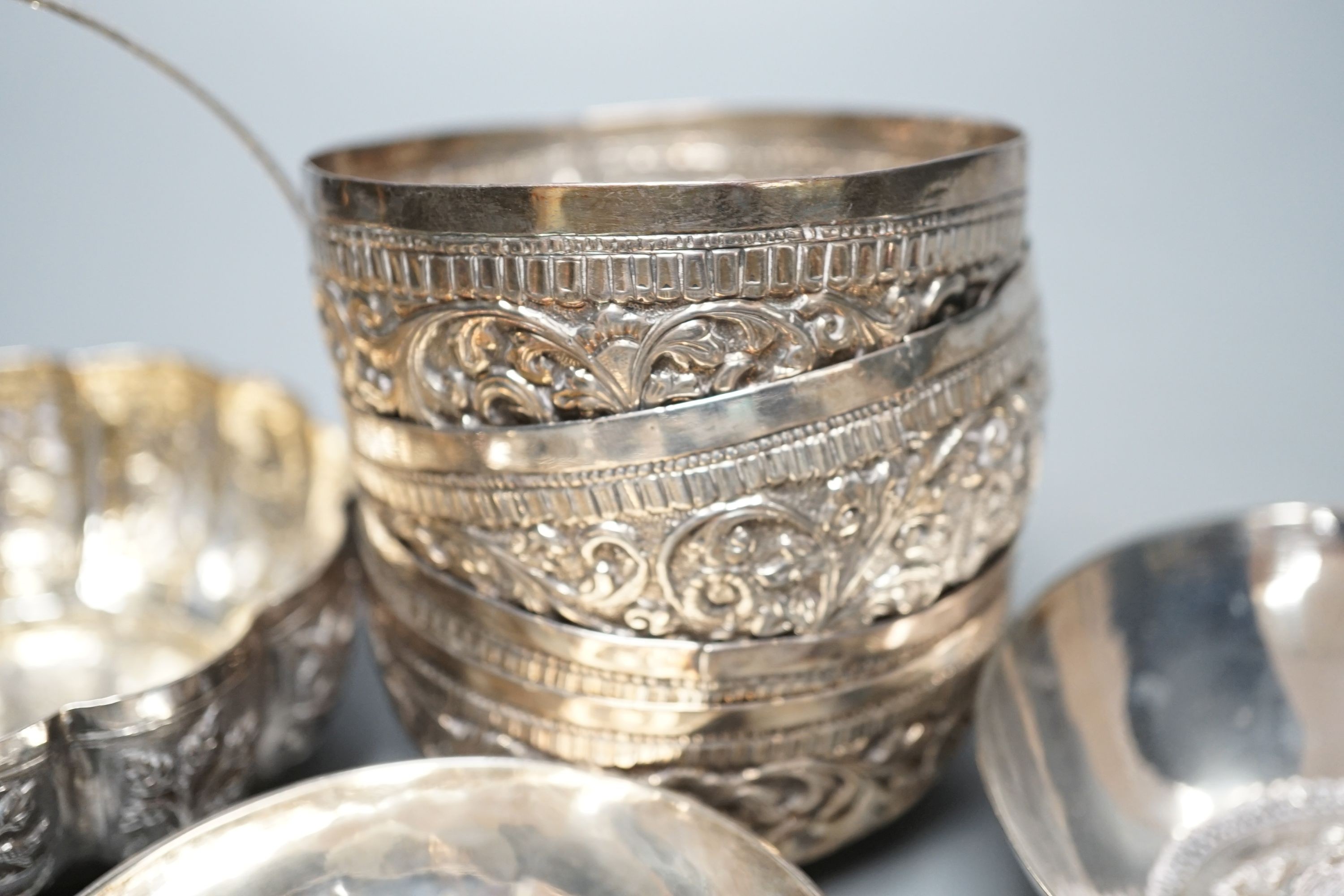 Four small Rangoon white metal bowls together with a simile basket and six small white metal bowls with heraldic motifs, gross 24.5oz.